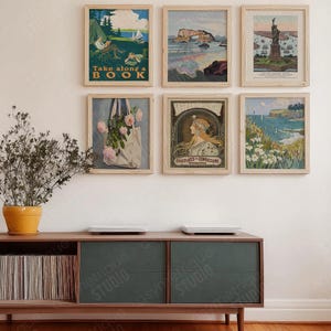 Könnte beinhalten: Eine Sammlung gerahmter Vintage-Kunstdrucke, die an einer Wand ausgestellt sind. Die Drucke zeigen verschiedene Szenen, darunter Landschaften, Illustrationen und Text. Die Rahmen sind aus hellem Holz. Der Text in einem der Drucke lautet "Take along a book".