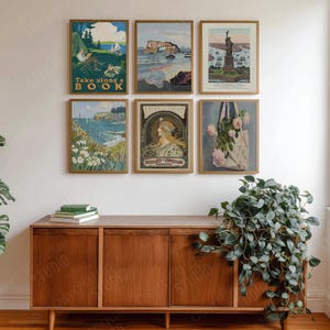 Op de afbeelding: Zes ingelijste vintage kunstprints. De prints tonen landschappen, een vrouw en een draagtas met bloemen. Eén print leest "Take along a BOOK". De frames zijn bruin en de kunst wordt tentoongesteld op een witte muur boven een houten kast.