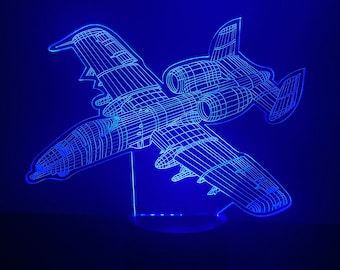 May include: A blue 3D printed night light shaped like an A-10 Warthog airplane. The light is on and illuminating the model.