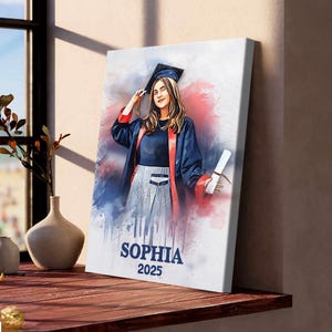 May include: A canvas print featuring a watercolor portrait of a graduate in a cap and gown. The artwork is in shades of blue, red, and white, with the name "SOPHIA" and the year "2025" printed at the bottom. The graduate is holding a diploma.