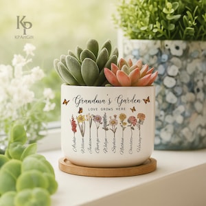 May include: White ceramic planter with the text "Grandma's Garden Love Grows Here" and a floral design with butterflies. The planter has eight names listed below the flowers: Archie, William, Jackson, George, Welyn, Sophia, Nathan, Charlotte, and Harvey.