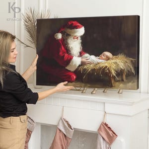 May include: A painting of Santa Claus in a red suit with a white beard, kneeling beside a baby in a manger. The baby is wearing a white robe and has a halo above its head. The painting is set against a dark background with a straw-filled manger.