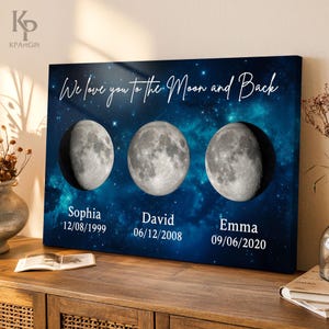May include: A blue canvas print with a starry night sky background. Three crescent moons are arranged across the canvas, each with a name and date below. The text reads "We love you to the Moon and Back".