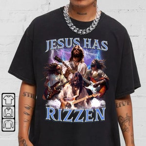 May include: Black t-shirt with a graphic of four figures playing electric guitars. The figures are dressed in long robes and have long hair. The text "JESUS HAS RIZZEN" is printed in blue letters on the shirt.