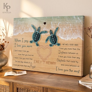 May include: A wooden canvas print featuring two teal sea turtles on a beach scene. The print includes the text "When I say I love you more" and "I love you the most", along with a heart and names.