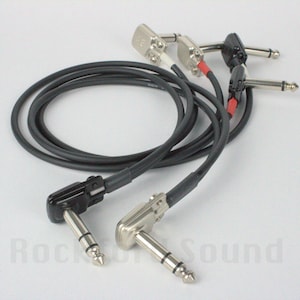 May include: A black and silver guitar cable with right-angle plugs on both ends. The cable is coiled and the plugs are visible.