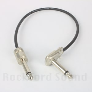 May include: A black guitar cable with a right-angle plug on one end and a straight plug on the other end. The cable is labeled "Patent Pending Low Noise Wire".