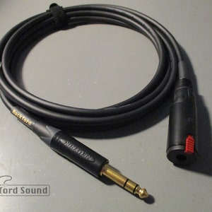 May include: A black audio cable with gold-plated connectors. One end has a 1/4 inch jack and the other end has a XLR connector. The cable is labeled "Rockford".