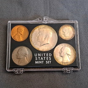 May include: A set of three ceramic mugs with a speckled, matte finish. The mugs are in shades of cream, light gray, and dark gray. Each mug has a simple, minimalist design, perfect for coffee or tea.