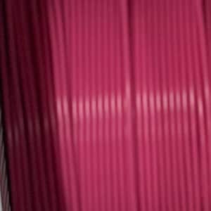 Puede incluir: Una bobina de cord&oacute;n magenta con una textura estriada, cil&iacute;ndrica y consistente. El cord&oacute;n est&aacute; enrollado firmemente en orientaci&oacute;n vertical, mostrando un color rosa intenso uniforme a lo largo de toda la longitud del material visible.