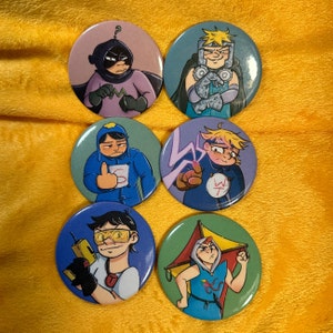 Op de afbeelding: Set van 6 ronde pinnen met cartoonfiguren met verschillende gezichtsuitdrukkingen en poses. De pinnen zijn kleurrijk en hebben een glanzende afwerking.