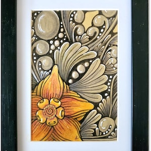 May include: A framed watercolor painting with a detailed floral design. The painting features a large orange flower with a yellow center and a background of swirling gray and white patterns.