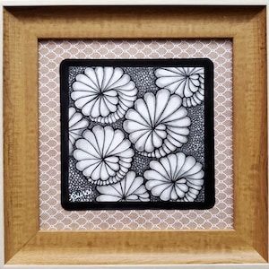 May include: Black and white framed artwork featuring a Zentangle design with a repeating pattern of stylized flowers. The artwork is signed "Laura" in the bottom left corner.