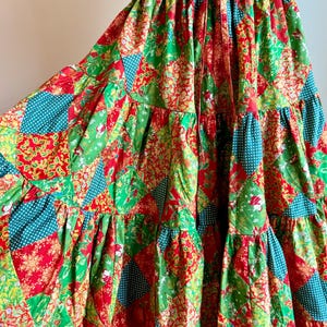 Puede incluir: Falda patchwork con tem&aacute;tica navide&ntilde;a. La falda presenta un dise&ntilde;o escalonado con paneles rojos, verdes y turquesas. La tela tiene estampados florales y de lunares. La cintura es roja con un cord&oacute;n.