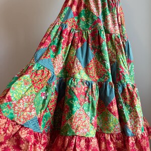 Puede incluir: Falda patchwork escalonada en rojo, verde y turquesa. La falda presenta estampados florales y de lunares. Tiene un dobladillo con volantes y una cintura con cord&oacute;n. La longitud de la falda es de aproximadamente 90 cm.