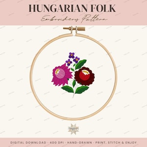 Op de afbeelding: Een houten borduurring met een wit stoffen paneel met een bloemmotief. Het patroon bevat een grote magentakleurige bloem, een donkerrode bloem, kleine paarse bloesems en groene bladeren. Bovenaan staat de tekst HUNGARIAN FOLK Embroidery Pattern.