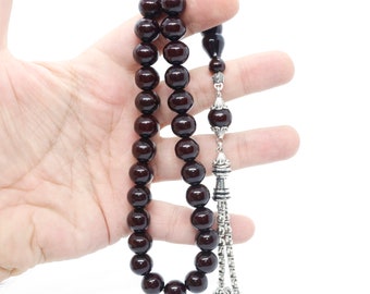 May include: A dark brown wooden prayer beads or rosary with silver accents and a tassel. The beads are round and smooth.