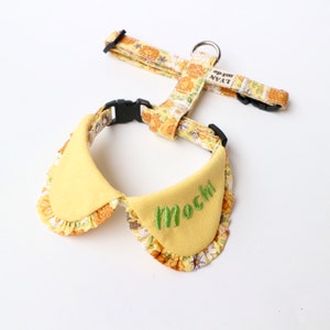 Op de afbeelding: Geel bloemenhondentuig met een bijpassende gele halsband met de naam "Mochi" geborduurd.
