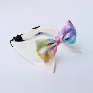 Op de afbeelding: Witte hondenhalsband met een kleurrijke geruite strik. De strik heeft een roze, gele, blauwe en groene geruite print.