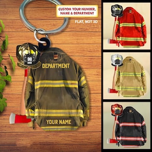 May include: A firefighter-themed keyring with a helmet, axe, and jacket design. The jacket is olive green with yellow stripes and the text "DEPARTMENT" and "YOUR NAME". The helmet displays the number "98" and "1056". The text "CUSTOM YOUR NUMBER, NAME & DEPARTMENT" is also visible.