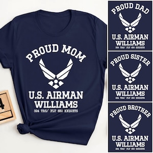 May include: Navy blue t-shirt with the text "PROUD MOM" and "U.S. AIRMAN WILLIAMS" in white. The shirt features a white Air Force emblem. Additional designs include "PROUD DAD", "PROUD SISTER", and "PROUD BROTHER" shirts.