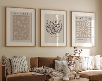 Puede incluir: Un sofá seccional marrón con una manta de tiro de patrón beige y marrón, tres almohadas con un patrón de rayas blancas y negras, y una mesa de café de madera. Tres impresiones enmarcadas con la palabra "MATISSE" y diseños abstractos cuelgan en la pared detrás del sofá.