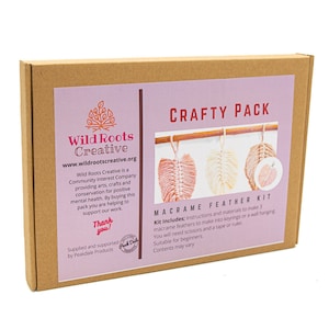 May include: A craft kit box featuring a pink, white and peach macrame feather kit. The box is labelled "Wild Roots Creative" and "Crafty Pack". The kit includes instructions and materials to make three macrame feathers.