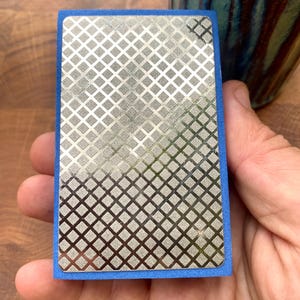May include: A diamond-shaped sharpening steel with a blue rubberized edge. The steel is designed for sharpening knives.