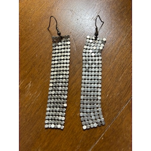 May include: A pair of silver-toned dangle earrings. Each earring features a series of small, round, metallic beads linked together to form a rectangular shape. The earrings have a hook closure.