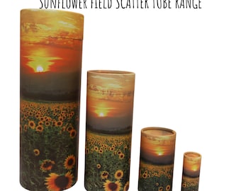 Puede incluir: Cuatro tubos de cartón biodegradables con un diseño de campo de girasoles y puesta de sol. Los tubos son de diferentes tamaños, siendo el más grande de aproximadamente 25 cm de alto.