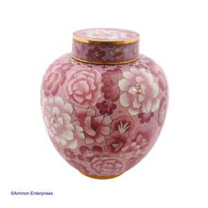 Può includere: Un'urna in ceramica rosa con un motivo floreale. L'urna ha un coperchio ed è decorata con fiori rosa e bianchi.
