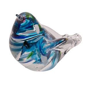 Könnte beinhalten: Eine Glasskulptur eines Vogels mit blauen, grünen und weißen Wirbeln. Der Vogel ist aus klarem Glas mit farbigen Glaseinschlussen gefertigt.
