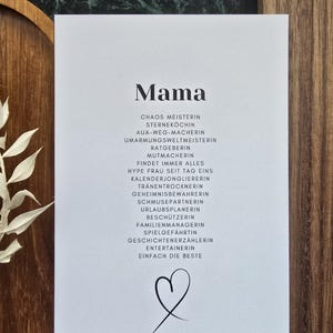 Könnte beinhalten: Eine weiße Karte mit dem Wort "Mama" in fetter Schrift, gefolgt von einer Liste deutscher Wörter. Am unteren Rand befindet sich eine einfache Herzillustration. Die Karte liegt auf einer Holzoberfläche.