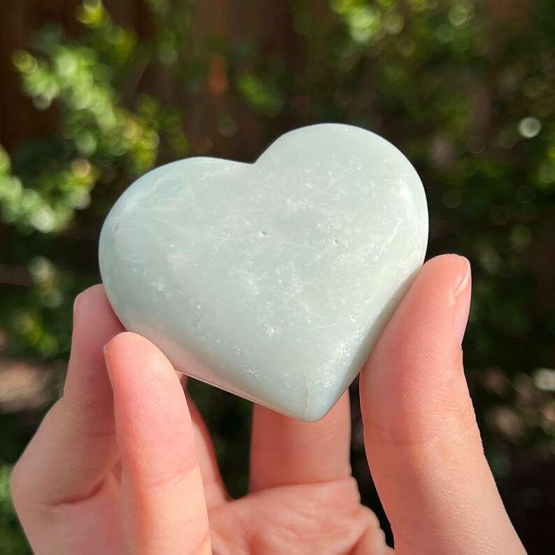 May include: A light green heart-shaped stone with a smooth, polished surface.