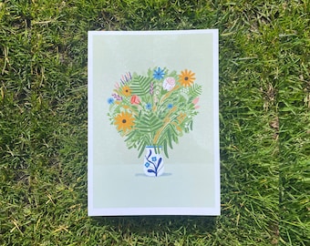 May include: A print of a bouquet of flowers in a blue and white vase. The flowers are a mix of pink, yellow, blue, and green.
