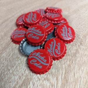 May include: A pile of red bottle caps with the words "Nuka Cola" printed in silver on top.