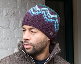 May include: A man wearing a brown knitted hat with a blue and green chevron pattern.