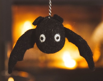 May include: A black felt bat with white eyes hanging in front of a fireplace.