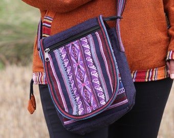 May include: A purple and blue patterned crossbody bag with a zipper closure. The bag has a long strap and is made of a woven fabric.