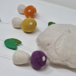 May include: A felt mushroom mobile with white, orange, yellow, purple, and green felt mushrooms. The mushrooms have white polka dots. The mobile is hanging from a white felt cloud.
