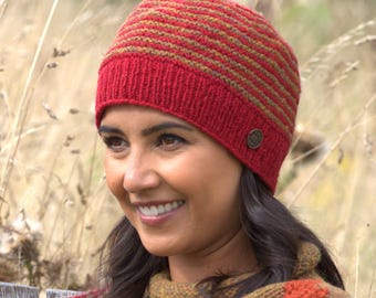 May include: A red and brown striped knit beanie with a ribbed brim. The hat features a small, round button detail on the side. The beanie is designed for warmth and style, perfect for cold weather.