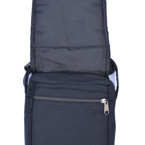 May include: A black canvas messenger bag with a zippered pocket and a flap closure. The bag has a strap and is open to reveal the interior lining.