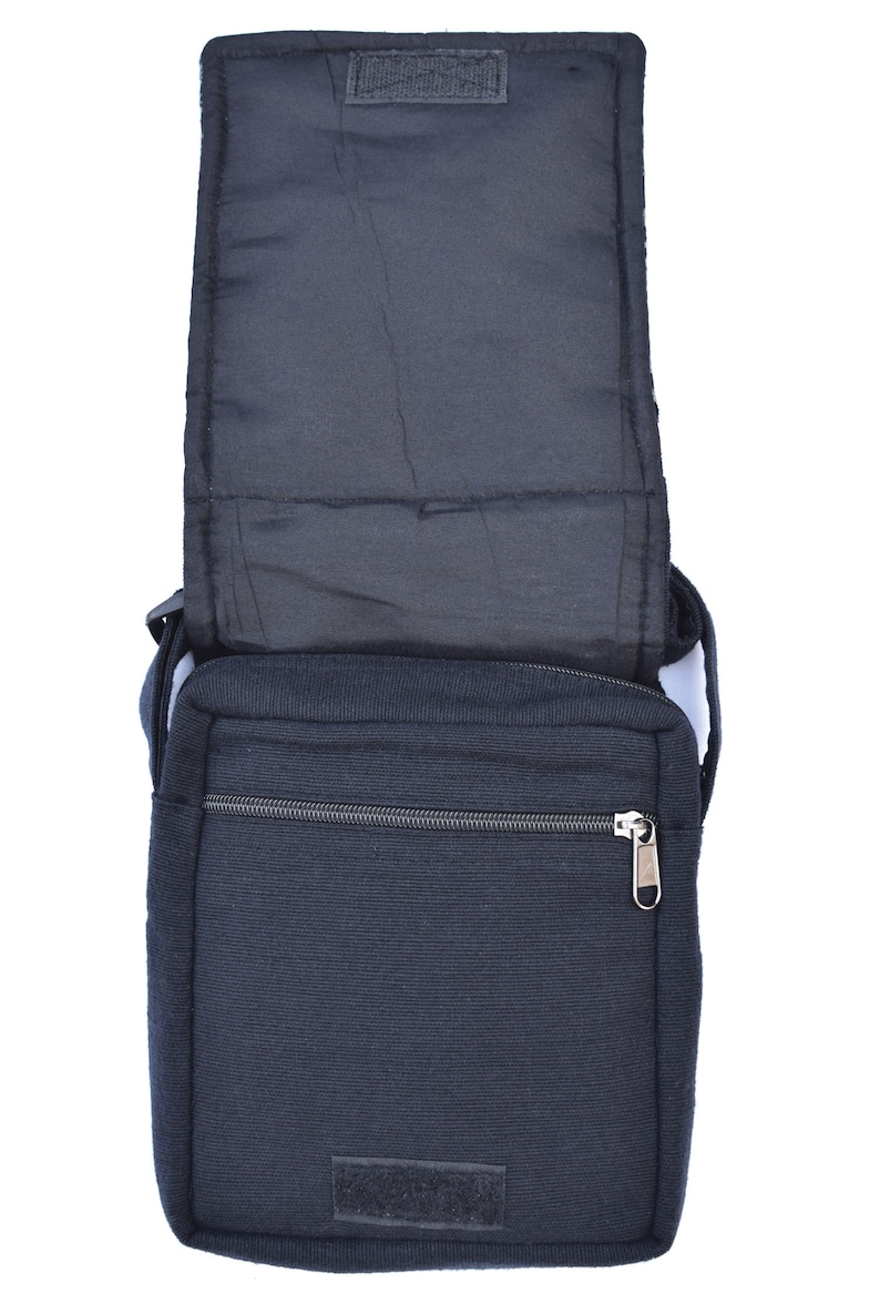 May include: A black canvas messenger bag with a zippered pocket and a flap closure. The bag has a strap and is open to reveal the interior lining.