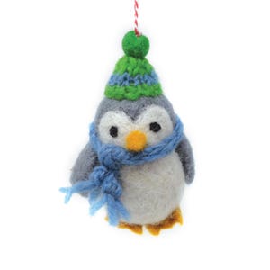 May include: A gray and white felt penguin wearing a green and blue knit hat and a blue scarf. The penguin is a Christmas ornament.