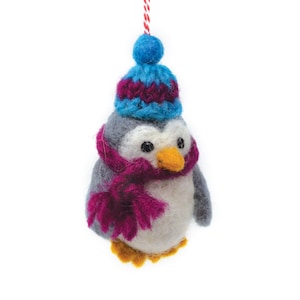 May include: A gray and white felt penguin wearing a blue and purple knit hat and a pink scarf. The penguin is a Christmas ornament.