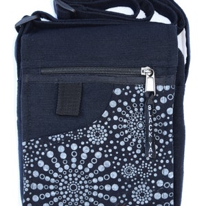 May include: Black canvas crossbody bag with a zipper closure and a small pocket on the front. The pocket has a white and black circular pattern with the text "Black Yak" on the side.