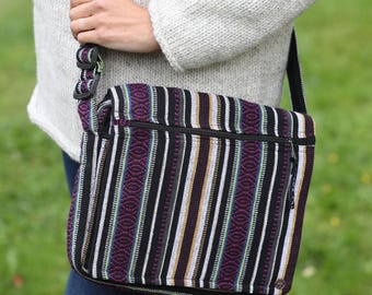 May include: A black and white striped messenger bag with a purple stripe and a zipper closure. The bag has a long adjustable strap.