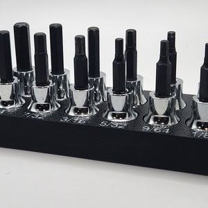 May include: A set of 18 black and silver hex bit sockets in a black holder. The sockets are labeled with their sizes: 5/16, 7/32, 3/16, 5/32, 9/64, 1/8, 7/64, 1/4, 3/8, 1/2, 5/16, 3/16, 1/16, 1/8, 5/64, 3/32, 1/4, 7/32.