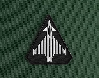 May include: A black triangular patch with a white embroidered image of a fighter jet.