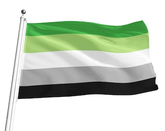 Puede incluir: Una bandera verde, verde claro, blanca, gris y negra ondeando al viento. La bandera está unida a un poste blanco.